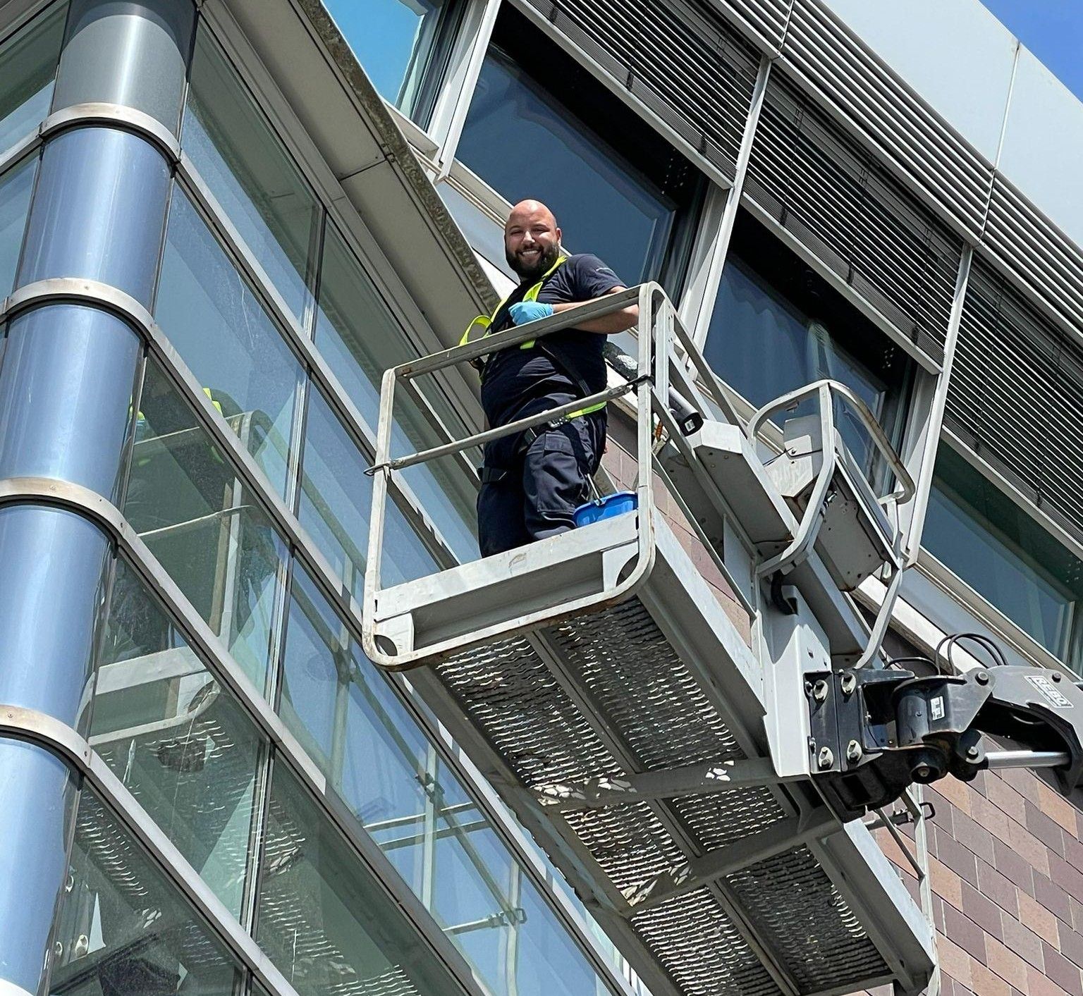 Mitarbeiter von AH Reinigung reinigt von einer Hubarbeitsbühne aus die Glasfassade eines Bürogebäudes